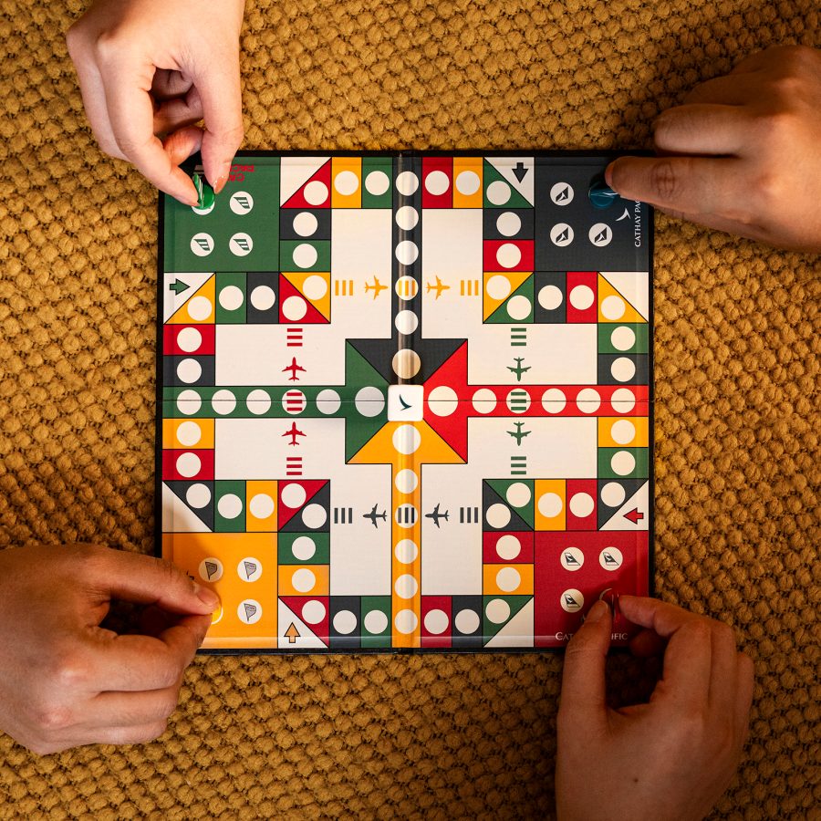 An overhead shot of four hands holding pieces on the Cathay Pacific aviation chess set 