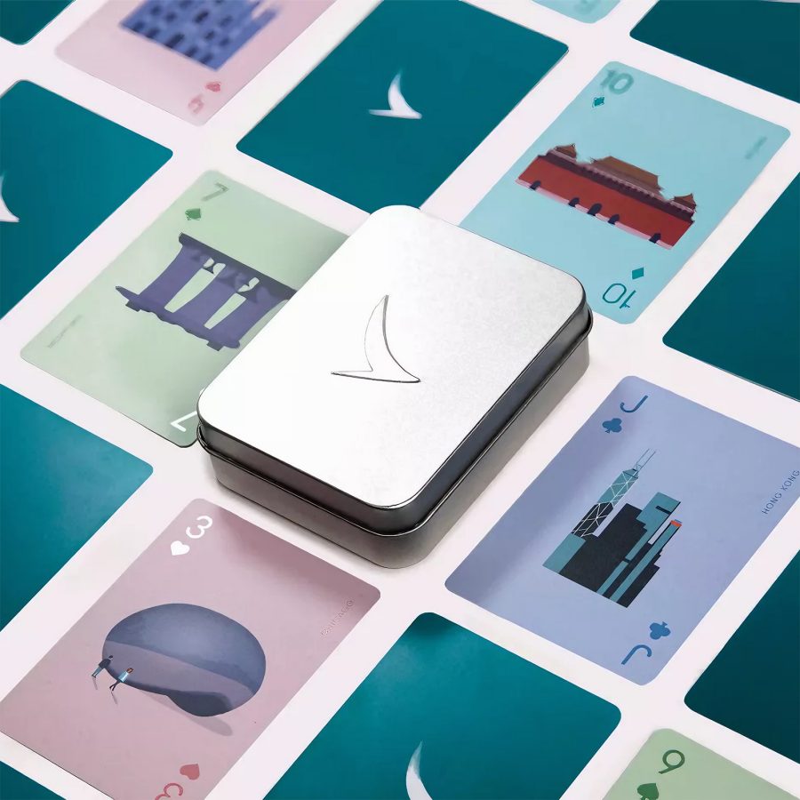 A lifestyle shot of the Cathay Pacific destination playing cards set laid out in rows featuring images of various iconic landmarks around the world and the tin box in the centre