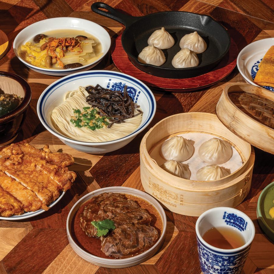 A family spread of various dim sum and Chinese dishes served at lulu BaoBao on modern wooden table