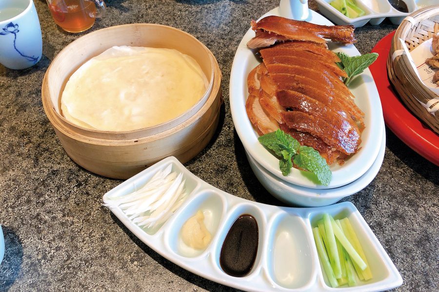 Roasted duck on a table alongside pancakes and garnishes, Bianyifang Roast Duck Restaurant.