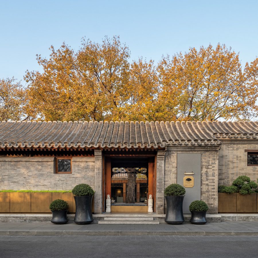 Exterior of Manradin Oriental Qianmen, Beijing,, with warm-hued trees behind. 