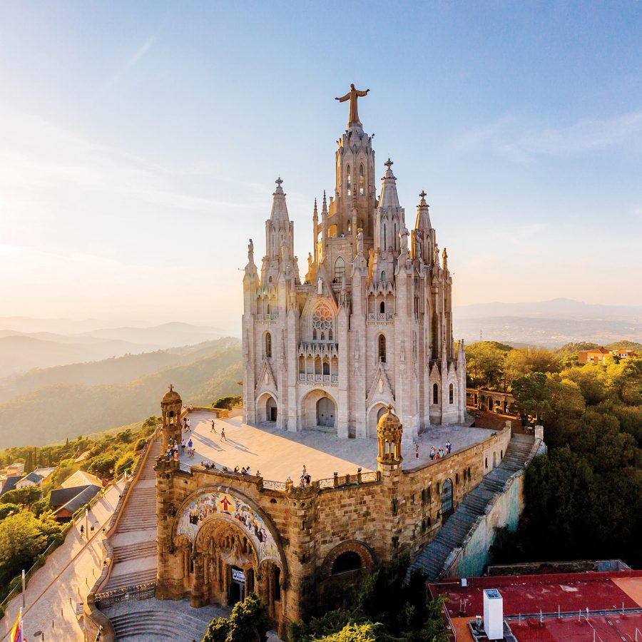 The Sagrat Cor basilica in Barcelona, a white gothic-style church at the top of a hill, on a sunny day.