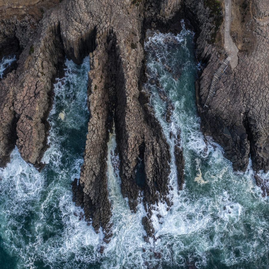 Waves crashing against the rugged, vertical Tojinbo Cliffs. 