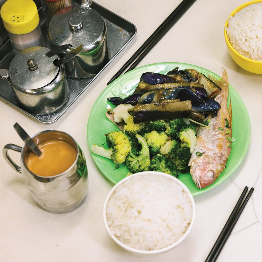 A cup of milk tea, two bowls of white rice and a plate of veggies and fish have been placed on a table at Pei Ho Counterparts.