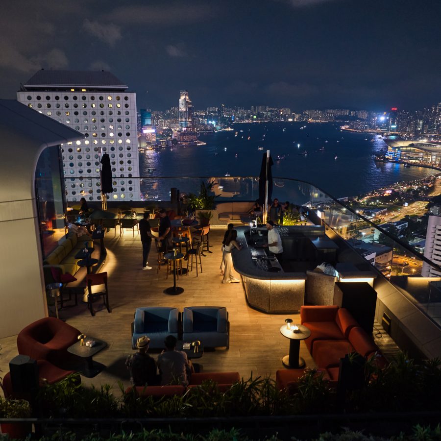 Cardinal Point’s outdoor seating area overlooks the glowing Victoria Harbour at night.