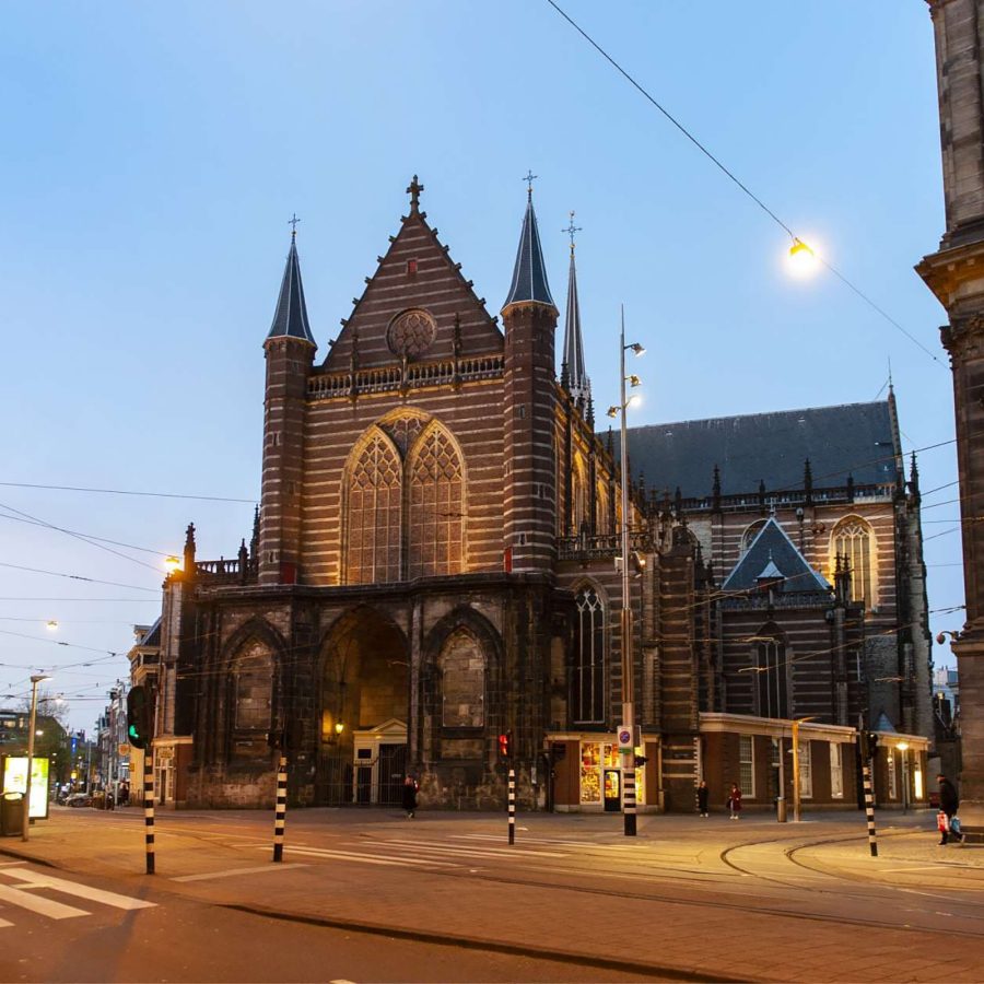 A street view of De Nieuwe Kirk The New Church in Amsterdam, Netherlands under an evening sky 