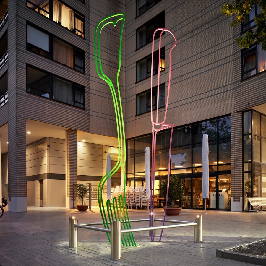 A view of a neon green and red fork and knife street art installation infront of a building in Amsterdam, Netherlands 