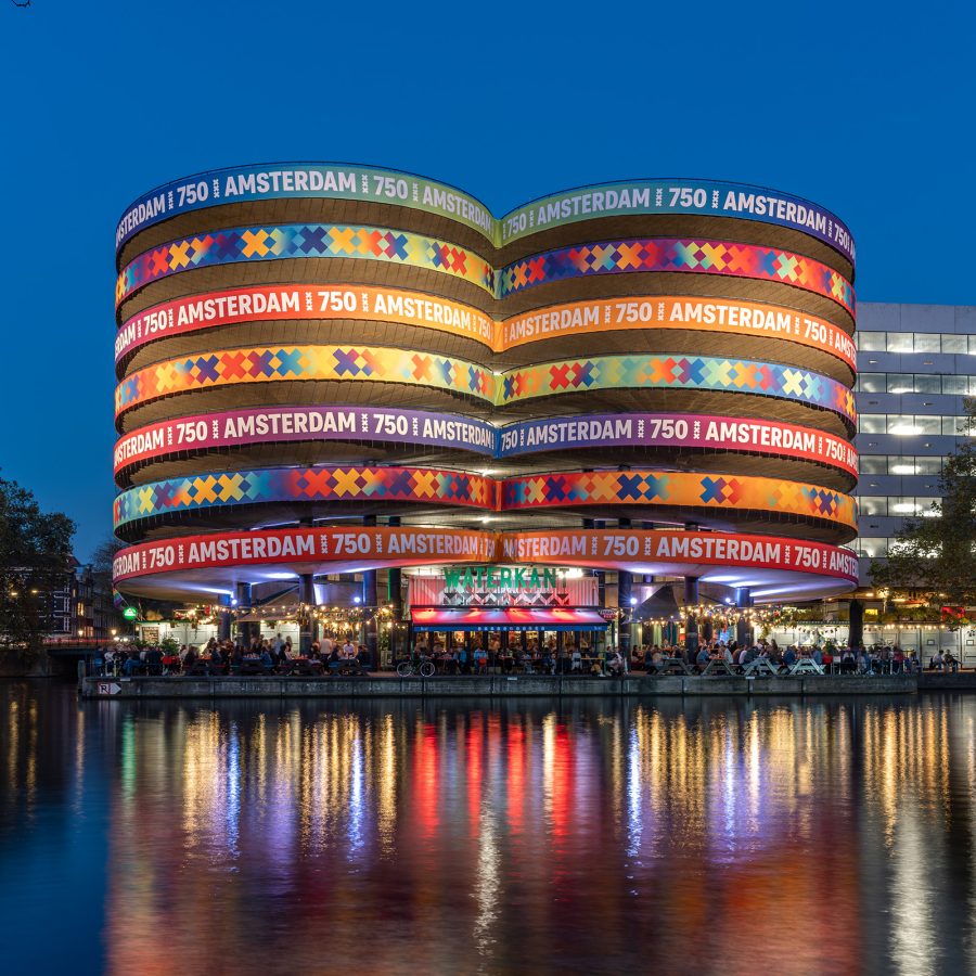 A view of Waterkant Amsterdam light up in different colours against the evening sky