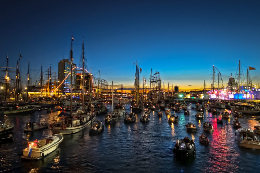 A view of a sea of ships scatter in the water at IJ Harbour in Amsterdam, Netherlands with a view of the sunset in the background 