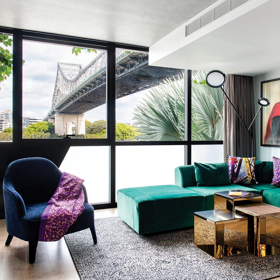 Jewel-toned interior of a room at Crystalbrook Vincent in Brisbane with a view of Story Bridge through the window.