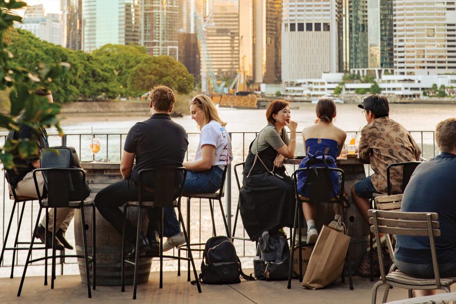 Groups of people sitting outside with drinks along the Brisbane River