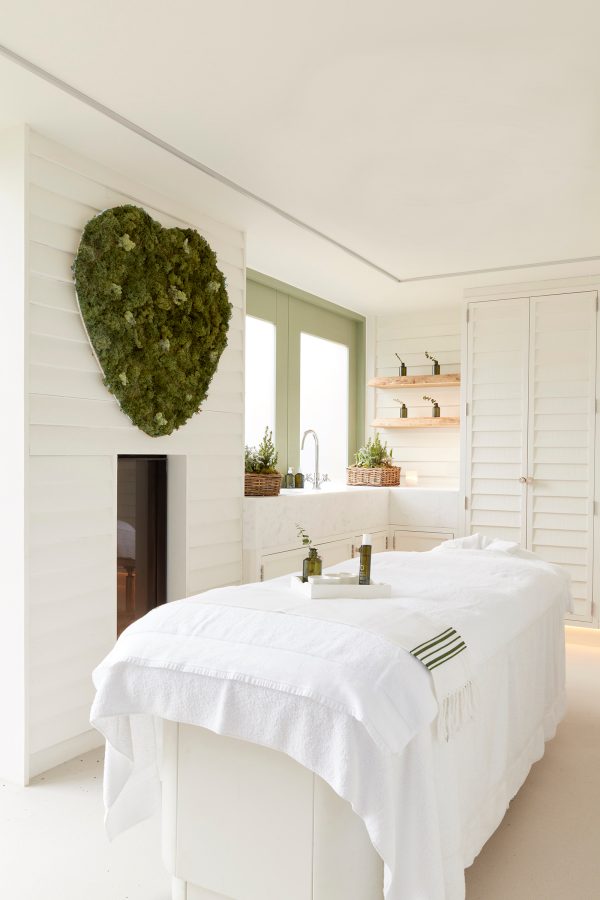 A brightly lit Bamford treatment room with a white spa bed.