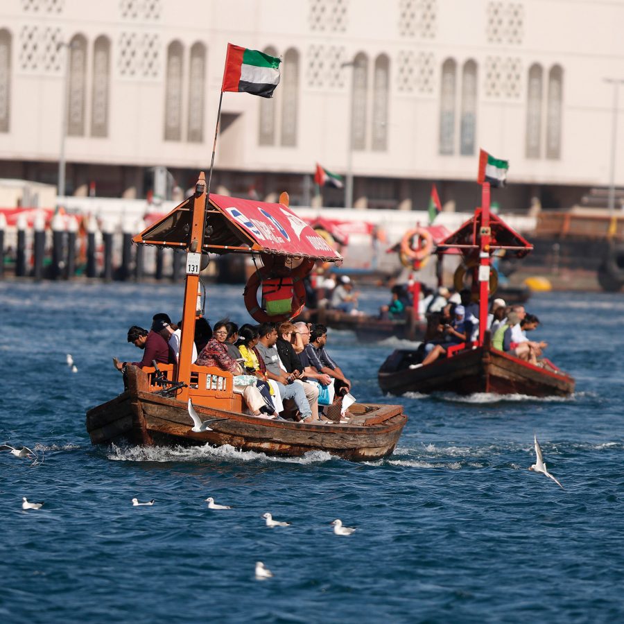 Exterior view of tourists aboard traditional abra (wooden boats) in Dubai Creek.