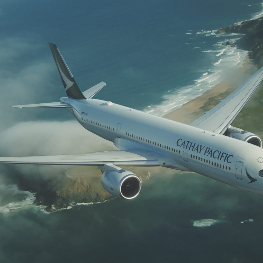 A Cathay Pacific plane flying over a coastline.