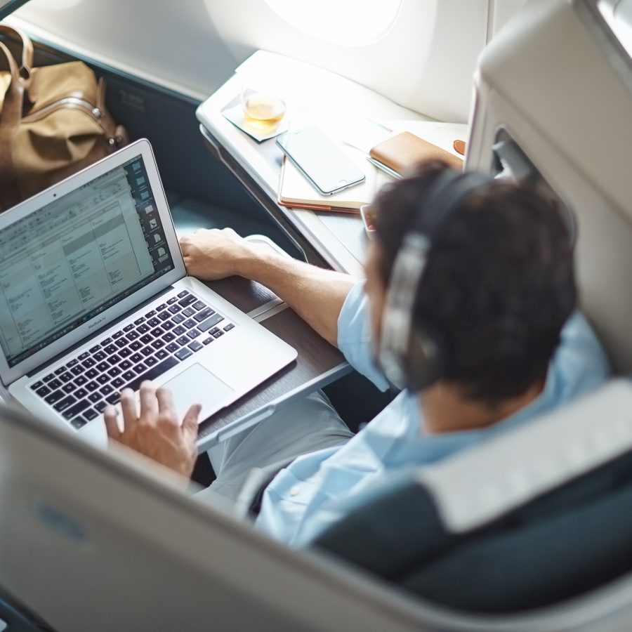 A man wearing headphones using a laptop on a Cathay Pacific flight. 