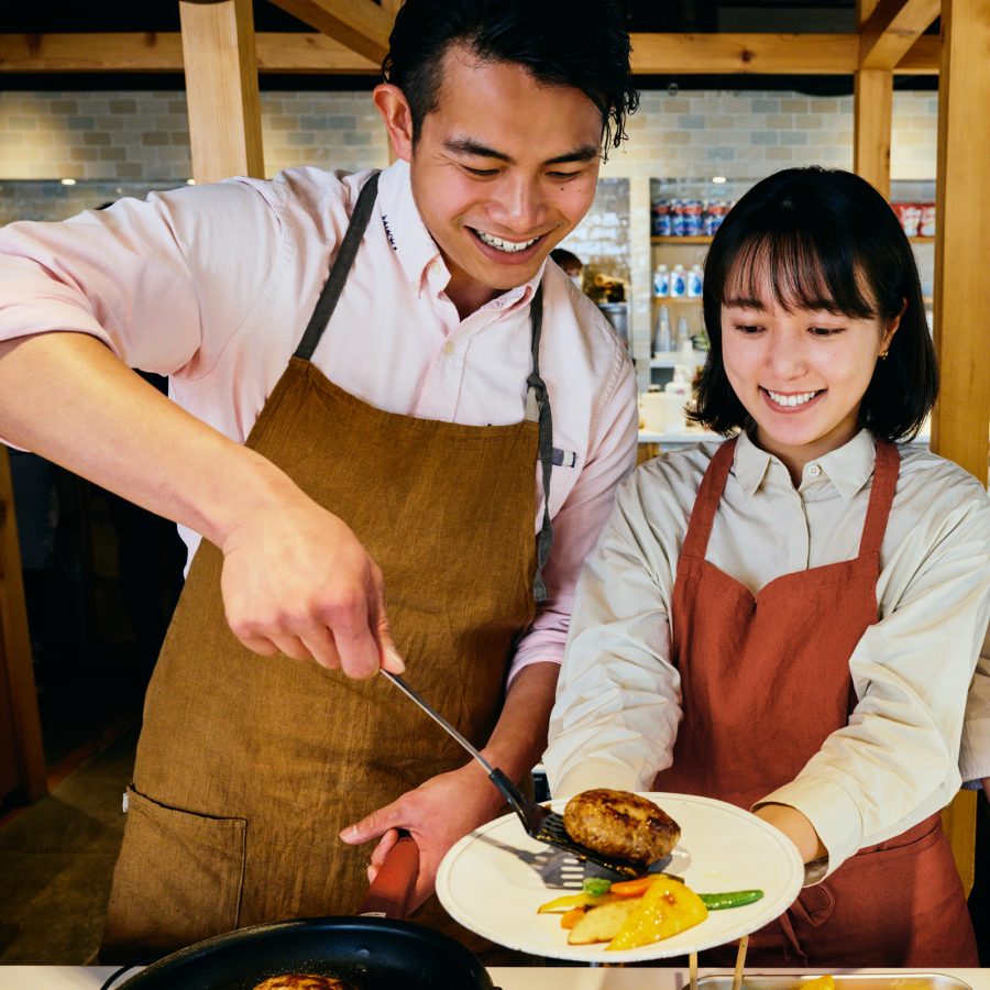 Interior view of three people in aprons cooking savoury food together at ABC Cooking Studio.