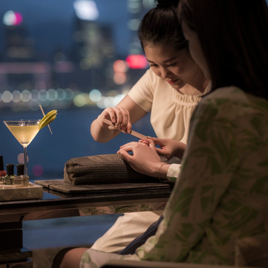 Interior view at nighttime of a woman getting a manicure while drinking a cocktail at Four Seasons.