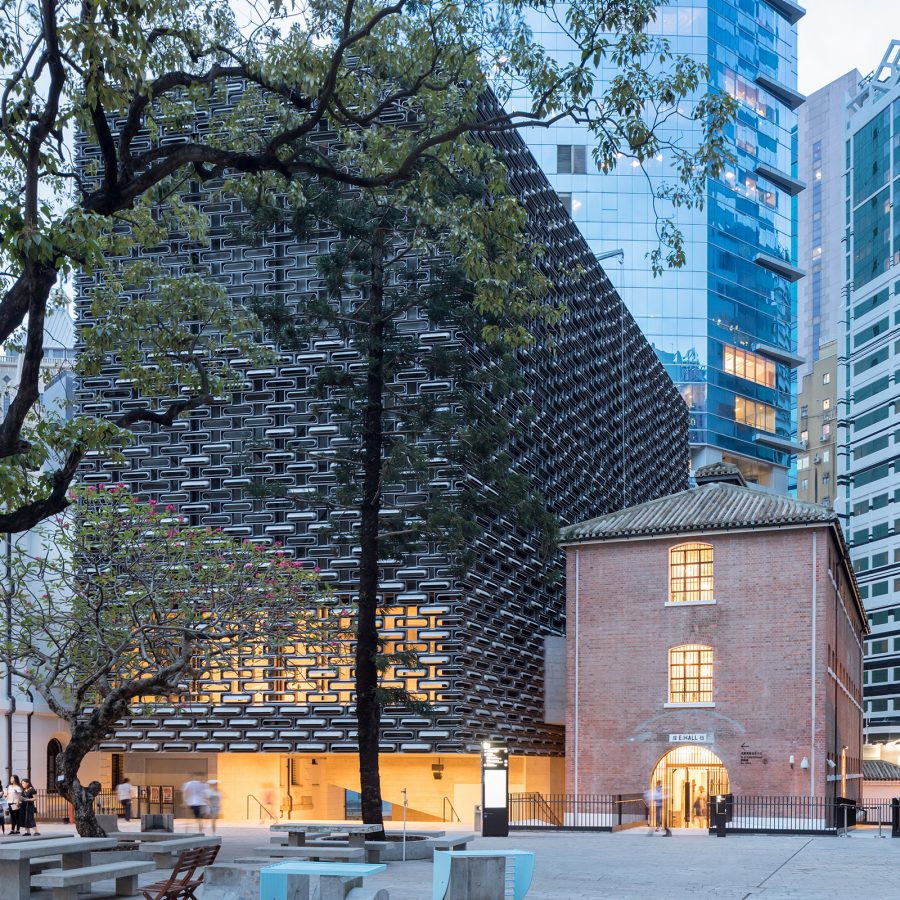 Exterior view at dusk of the Prison Yard at Tai Kwun, with an old tree on the left and JC Contemporary art space at the rear.