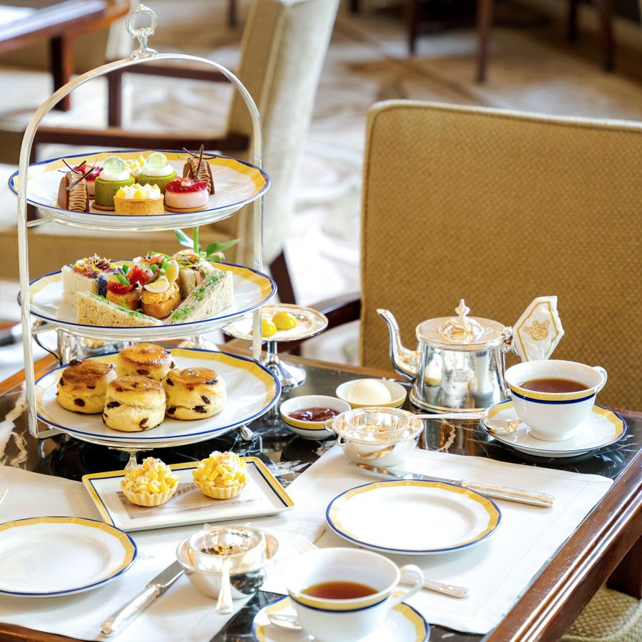 Interior view of a table set for tea, with scones, cakes, tea and sandwiches at The Peninsula.