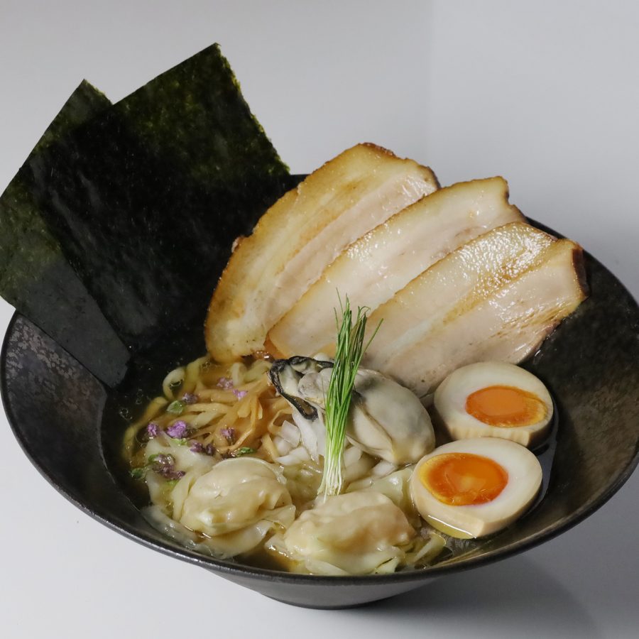 A closeup of a bowl of ikasu ramen, featuring Japanese oysters, scallops, slices of roast pork, dried seaweed and onsen egg, served at Next Shikaku.