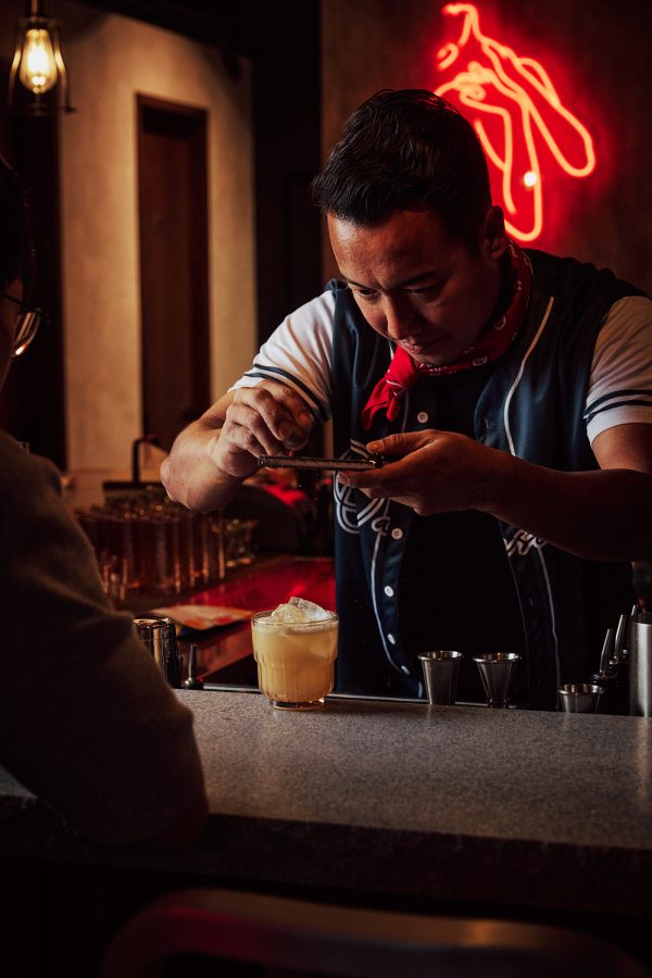 Mixologist Alex Pun adding garnish to a cocktail at Bar Oasis.