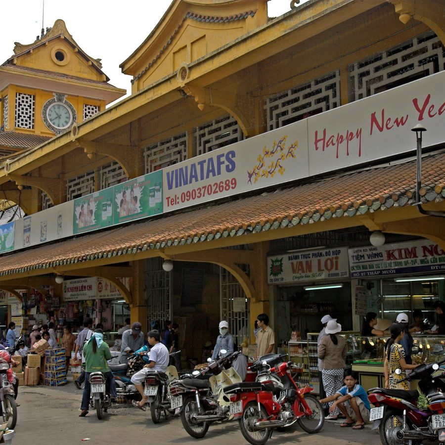 Exterior view of Binh Tay Market in Ho Chi Minh City, with motorbikes parked outside.