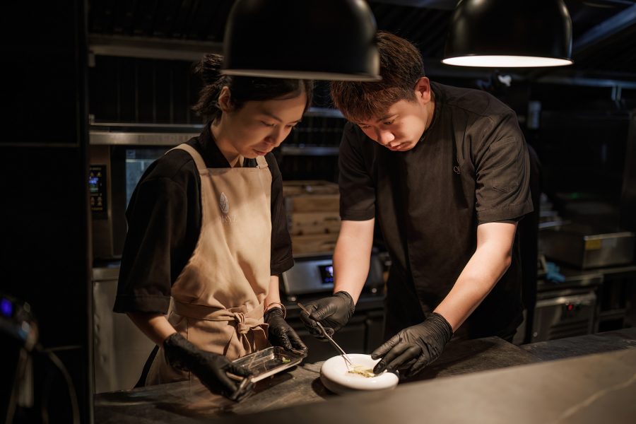 Interior view of two chefs preparing a dish in the kitchen of Oryz Saigon. 