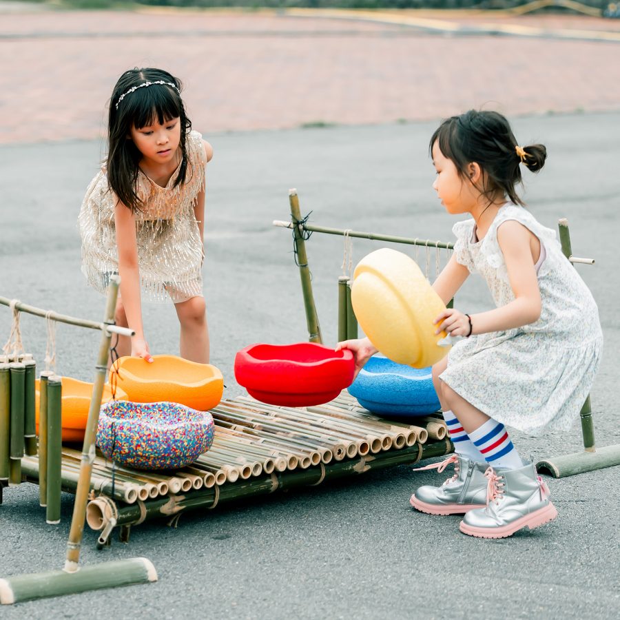 Two young girls play with bamboo tools at SummerFest Hong Kong. 