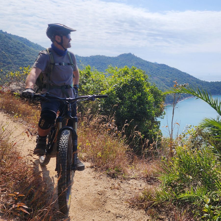 A person on a bicycle on a trail overlooking a body of water in Lantau South Country Park. 