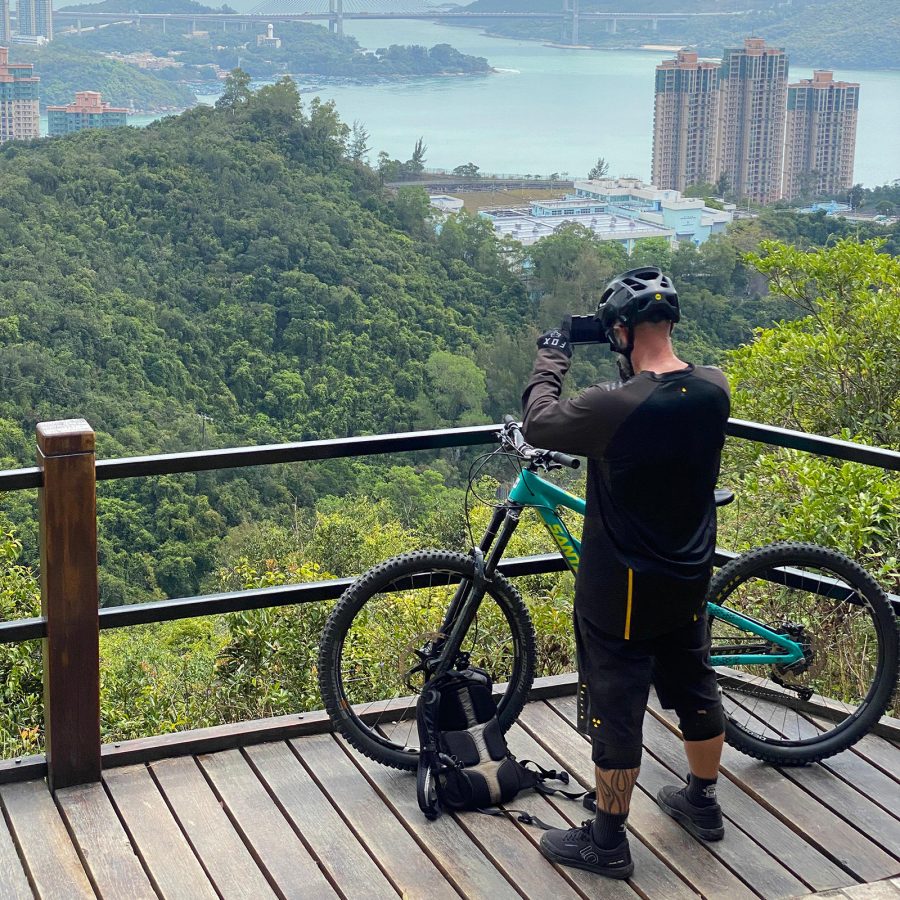 A person standing next to his bicycle, taking a photo of Hong Kong’s landscape.