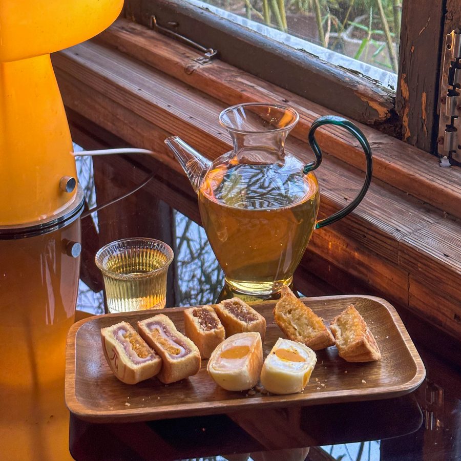 Tea snacks have been divided into portions and placed on a wooden tray next to a jug of tea and a mushroom lamp at Ajizai. 