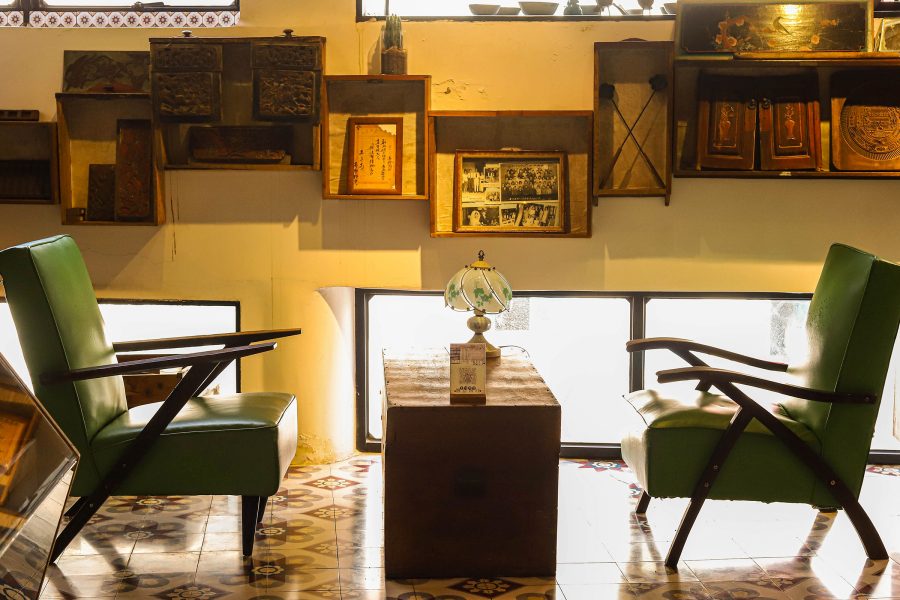 Green cushioned chairs face each other over a wooden coffee table at Ajizai. 