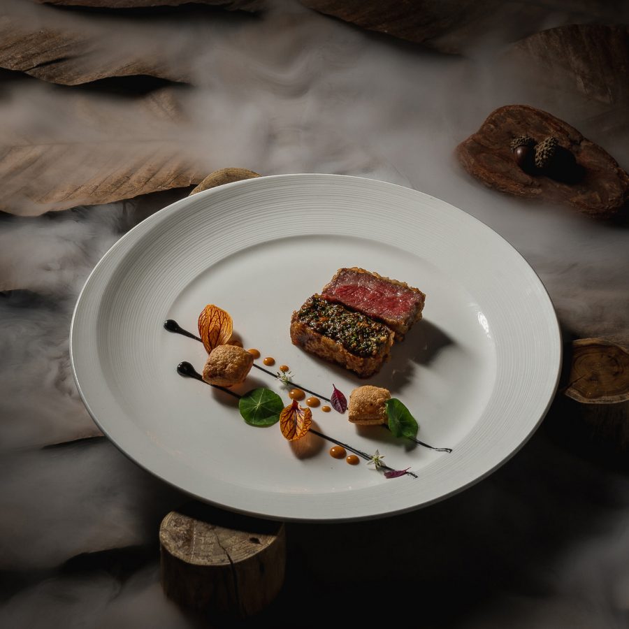 Two slices of red meat are placed on a garnished plate at Flame Restaurant. 
