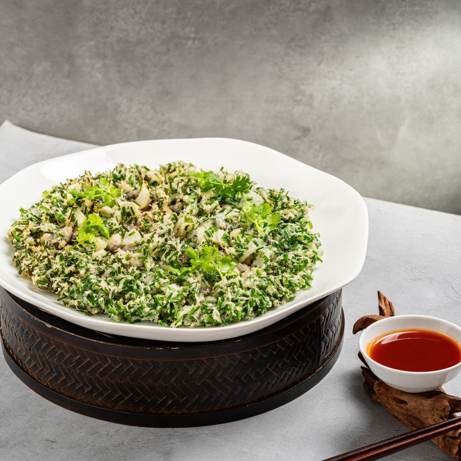 A green and spiky looking dish is displayed alongside a red sauce at Si Xia Li.   