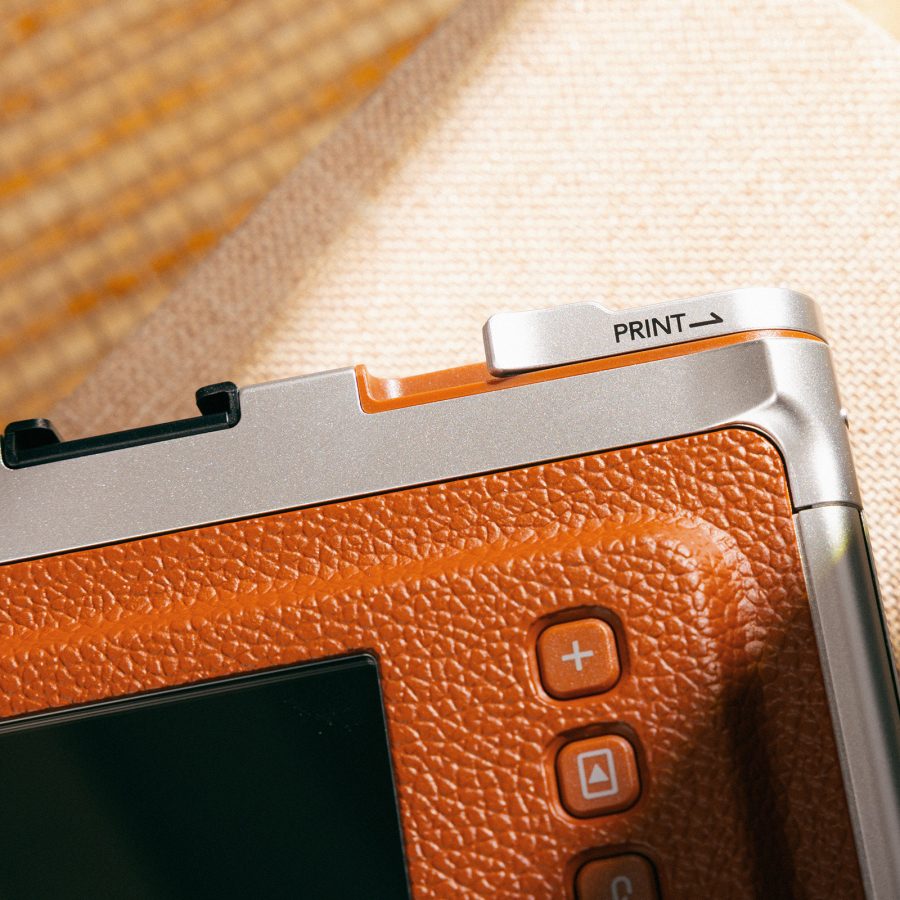 Close-up on the print button on the back of the Fujifilm Instax Mini Evo.