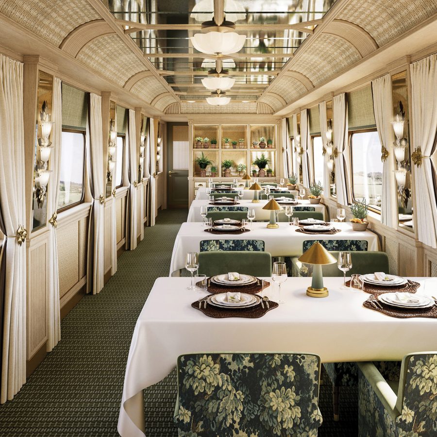 The elegant interiors of Belmond Train’s Britannic Explorer dining carriage during day time with a view of natural surroundings seen through the windows