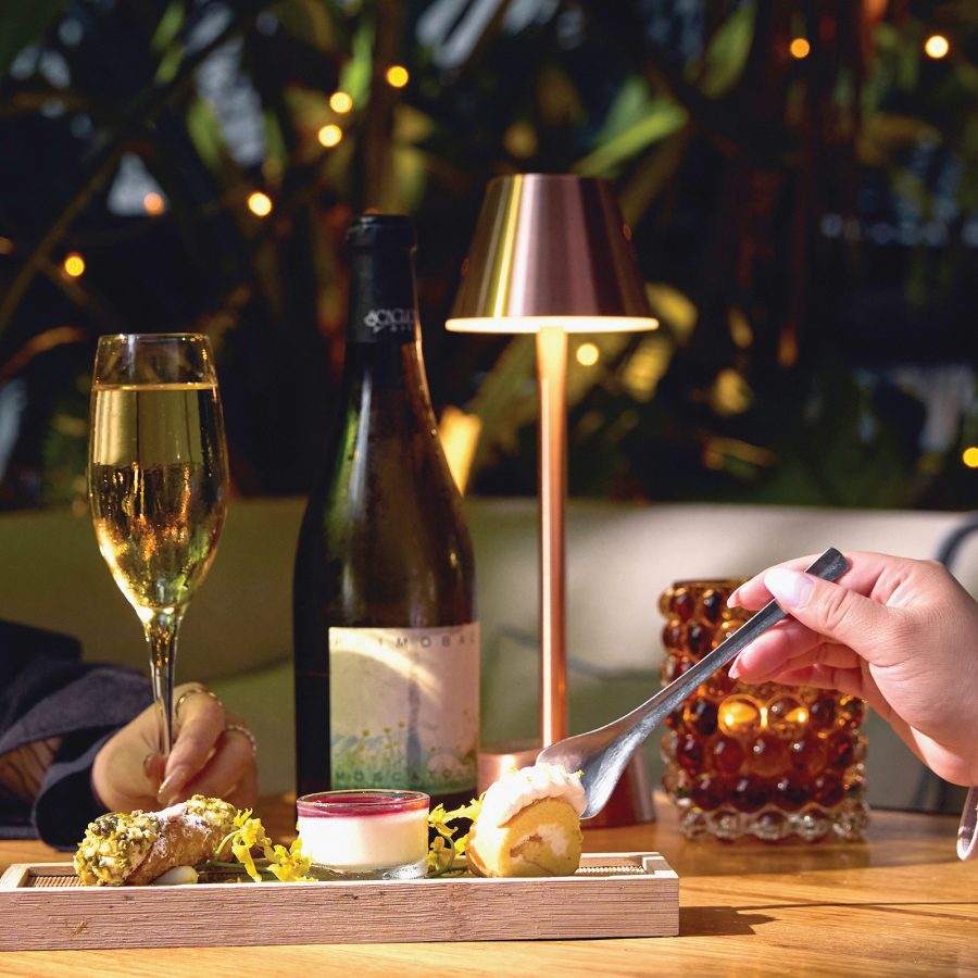Closeup of two people dining with a bottle of wine in a hotel restaurante with modern decor in the backdrop