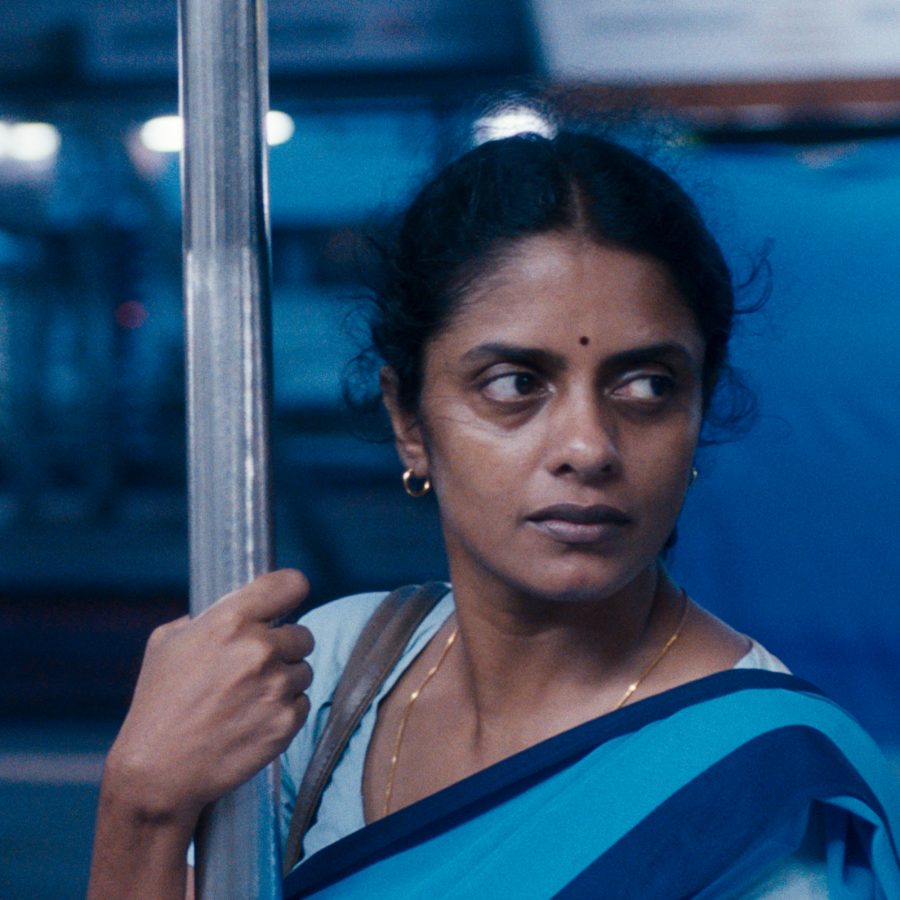 A woman in a blue sari rides on a subway train in a scene from All We Imagine as Light.