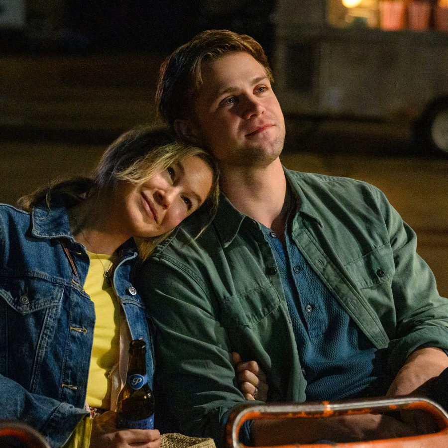A woman rests her head on the shoulder of a young man as they sit on chairs outdoors at night, in a scene from Bridget Jones: Mad About the Boy.