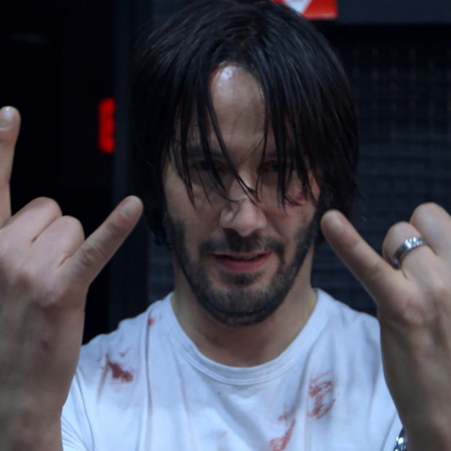 A man with dishevelled hair and blood smeared on his t-shirt holds his hands up to the camera in a scene from Wick is Pain. 