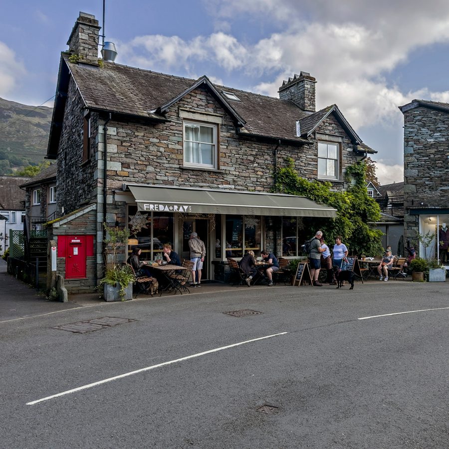 Low buildings built from brick sit on the side of the road in Grasmere, UK. 