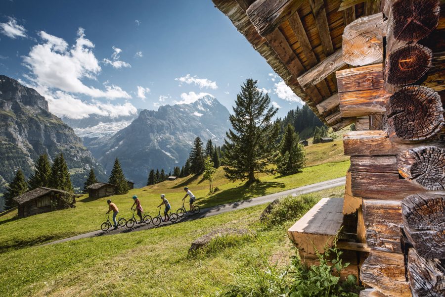 Cyclists travel down a slope in Grindelwald. 