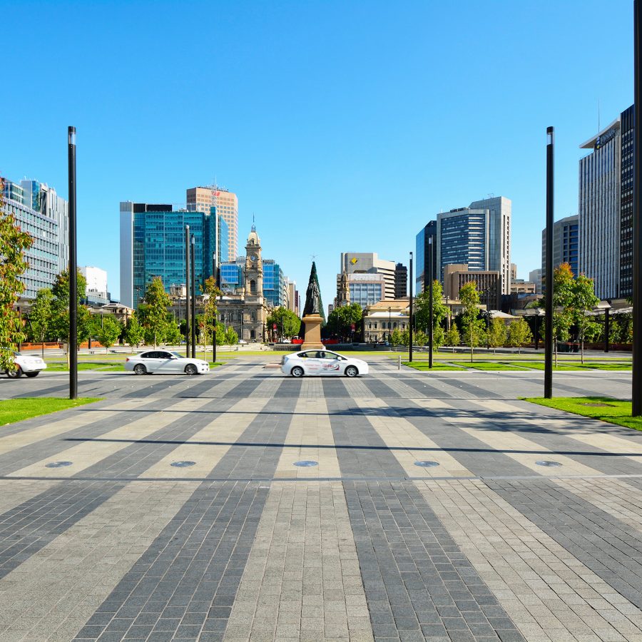 A view of Adelaide’s Victoria Square shows a spacious avenue lined with landscaped trees, a statue, a large Christmas tree in the distance and a clock tower.