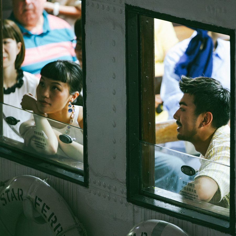 A man and woman ride the Star Ferry and gaze out of the windows.  