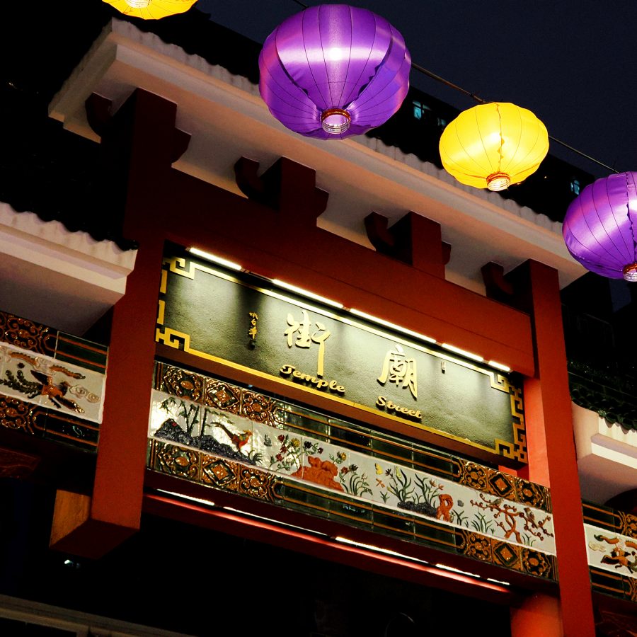 Lanterns and lights illuminate the red gate at the entrance of Temple Street Night Market.