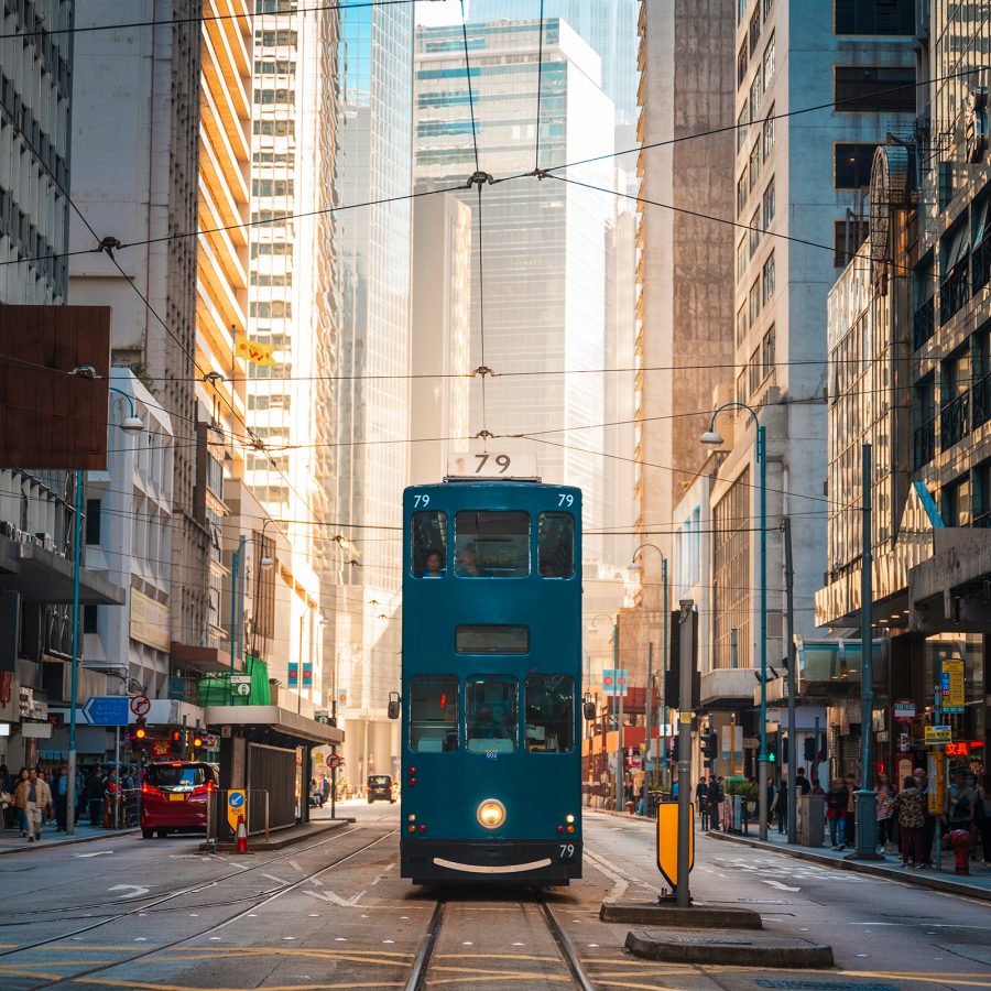 A blue tram driving through Hong Kong.