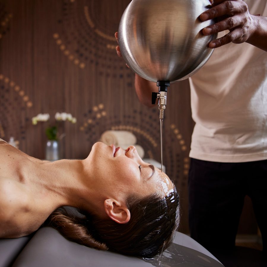 A woman relaxes as a massage therapist pours oil over her forehead at Palazzo Fiuggi in Italy 