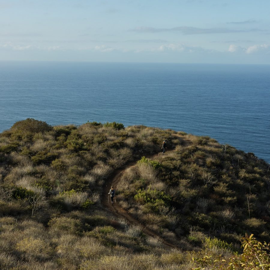 People hiking a winding coastal trail in Malibu
