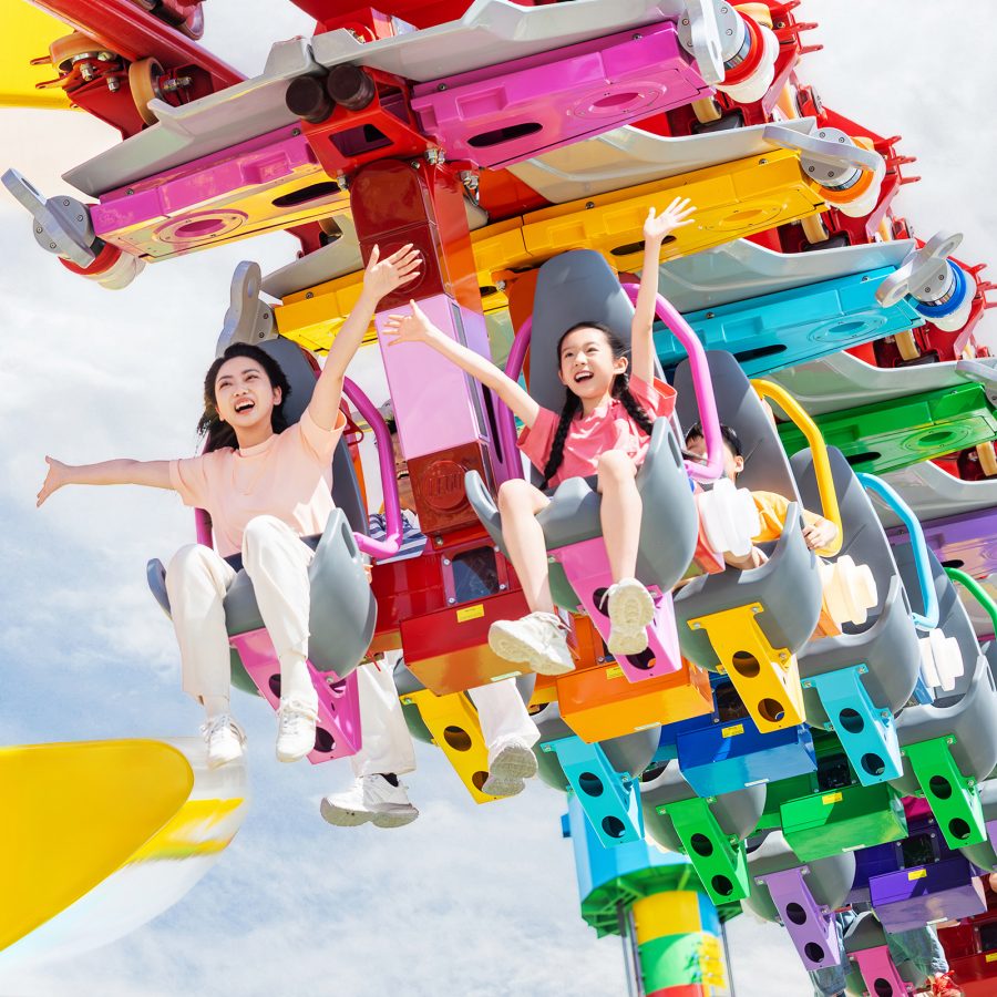 People cheering while riding a colourful roller coaster ride at Legoland Shanghai Resort, Shanghai, China 