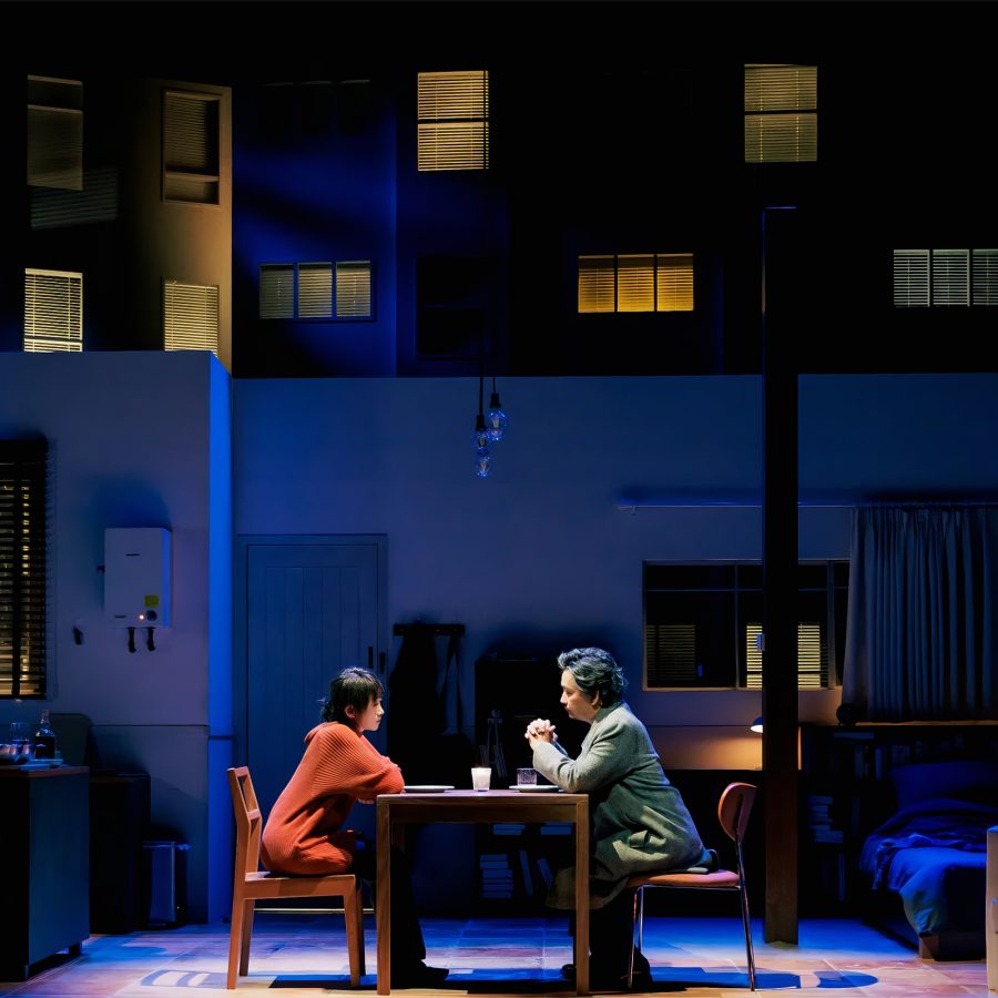 Two performers sit across the table from each other as part of a Shenzhen performance of Skylight.